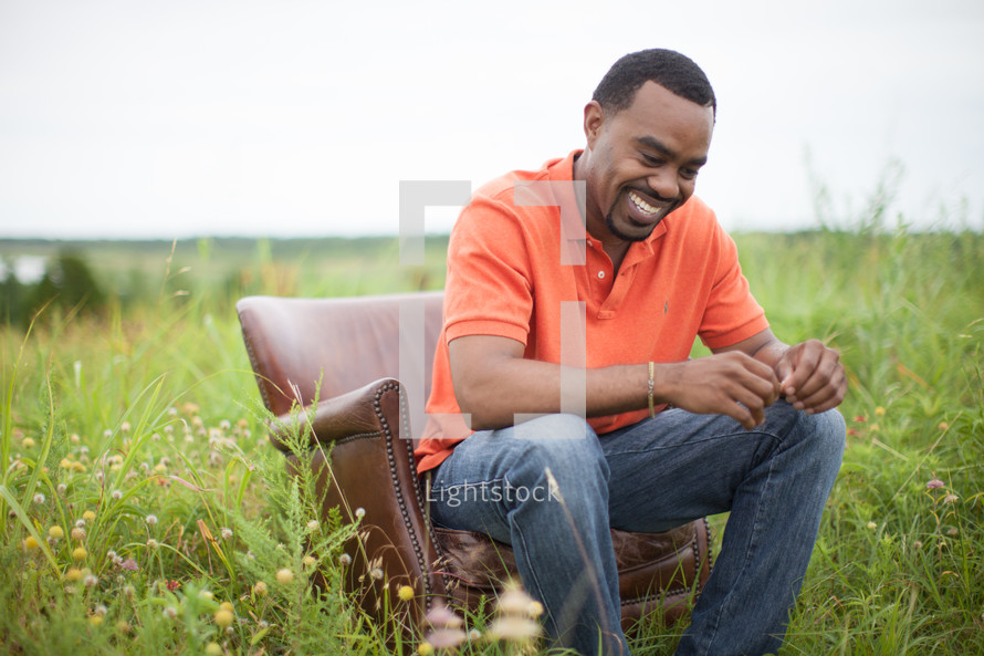 African-American man sitting in a chair in a field relaxing 