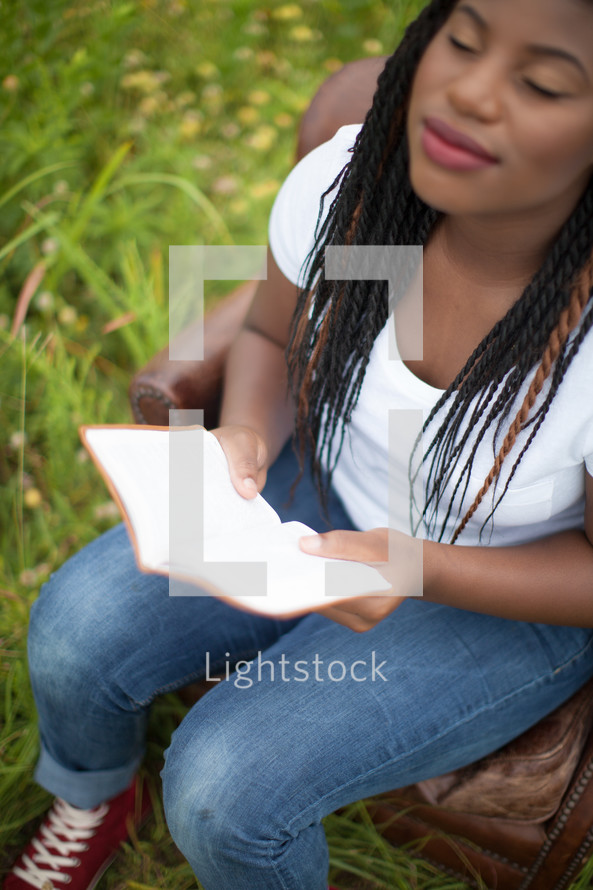 woman reading a Bible sitting outdoors 
