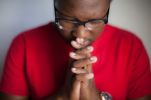 African-American man with praying hands and head bowed 