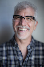 face of a man wearing reading glasses with a white beard 