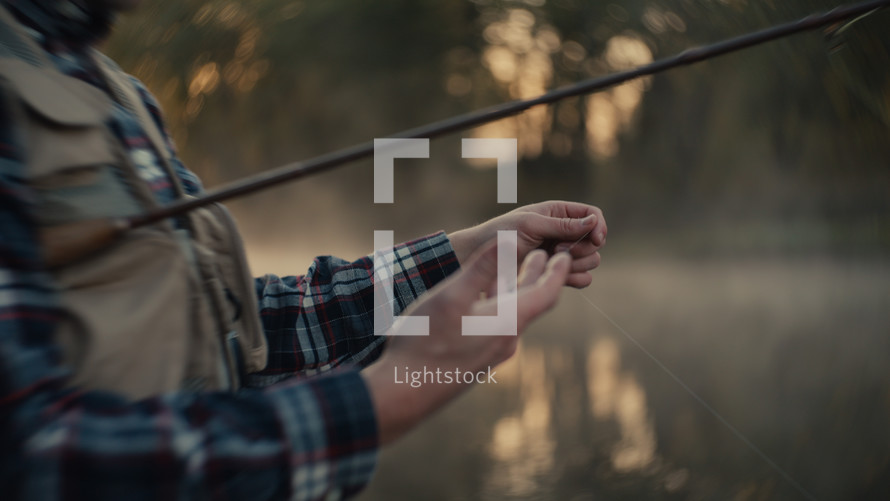 Young fly fisherman casting on a foggy river at sunrise