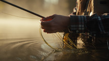 Young fly fisherman casting on a foggy river at sunrise