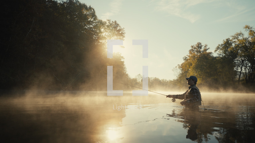 Young fly fisherman casting on a foggy river at sunrise