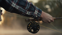 Young fly fisherman casting on a foggy river at sunrise