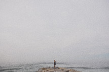 woman standing on a jetty looking at the ocean