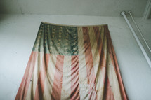 an old weathered American flag hanging on a wall 
