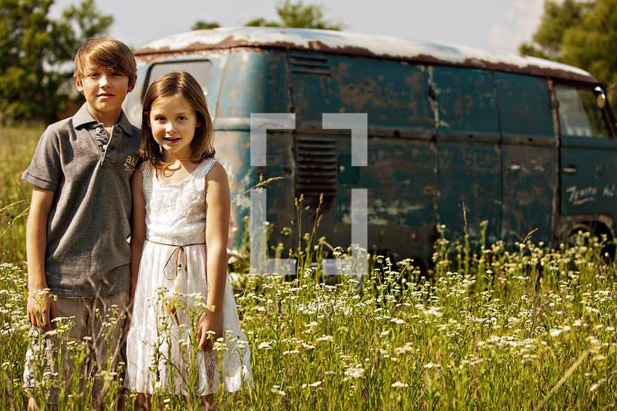 brother and sister in front of an old van in a field