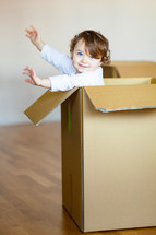 toddler playing in a cardboard box 