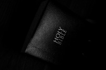 A black Bible on a dark background.