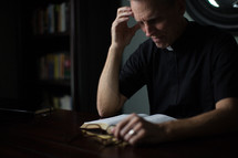 A minister intently studies the Bible at a desk.