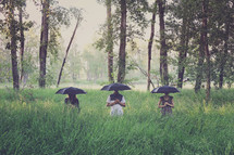 people holding umbrellas in the woods 