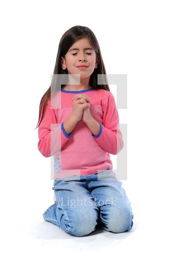 Young girl kneeling with her hands folded in prayer