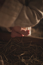 The feet of baby Jesus near the manger.