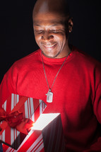 African American man looking happily into a gift box full of light.