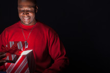 African American man looking happily into a Christmas gift box full of light.