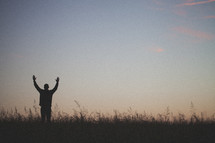 silhouette of a man with his hands raised to God 