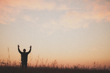 silhouette of a man with his hands raised in worship to God 