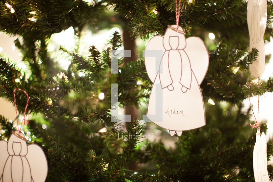 a white angel ornament hanging on a Christmas tree 