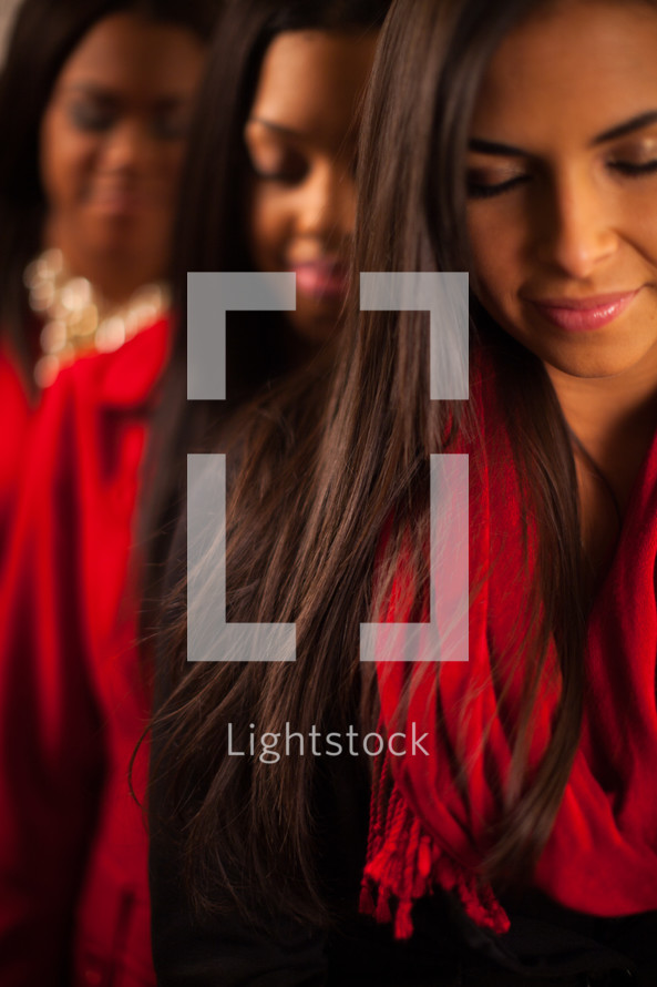 three young African-American women with heads bowed in prayer 