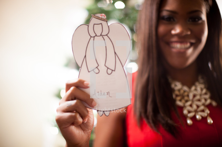 A young African-American woman holding a paper angel 