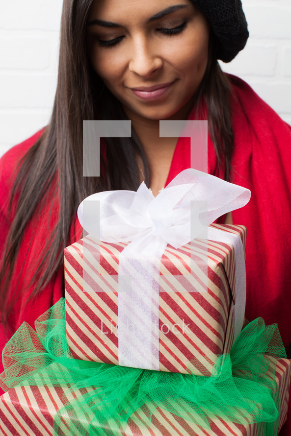 an African-American woman with head bowed holding Christmas gifts 