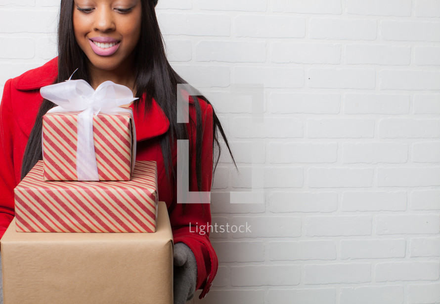 an African-American woman holding wrapped Christmas gifts 