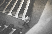 man walking down the aisle of an empty church