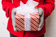 hands in gloves holding a wrapped Christmas gift 