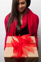 An African American woman with head bowed holding a wrapped Christmas gift 
