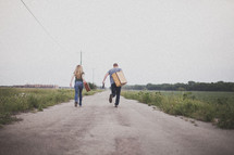 man and woman carrying luggage running down a road