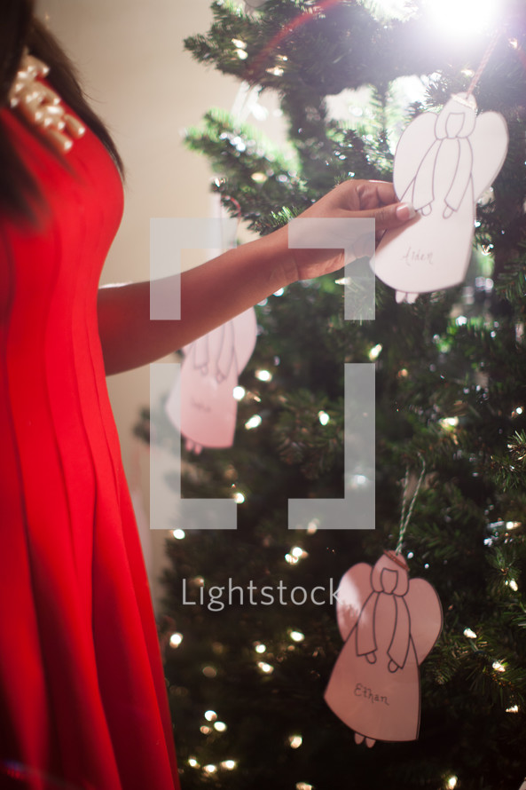 an African-American woman touching an angel ornament on a Christmas tree 
