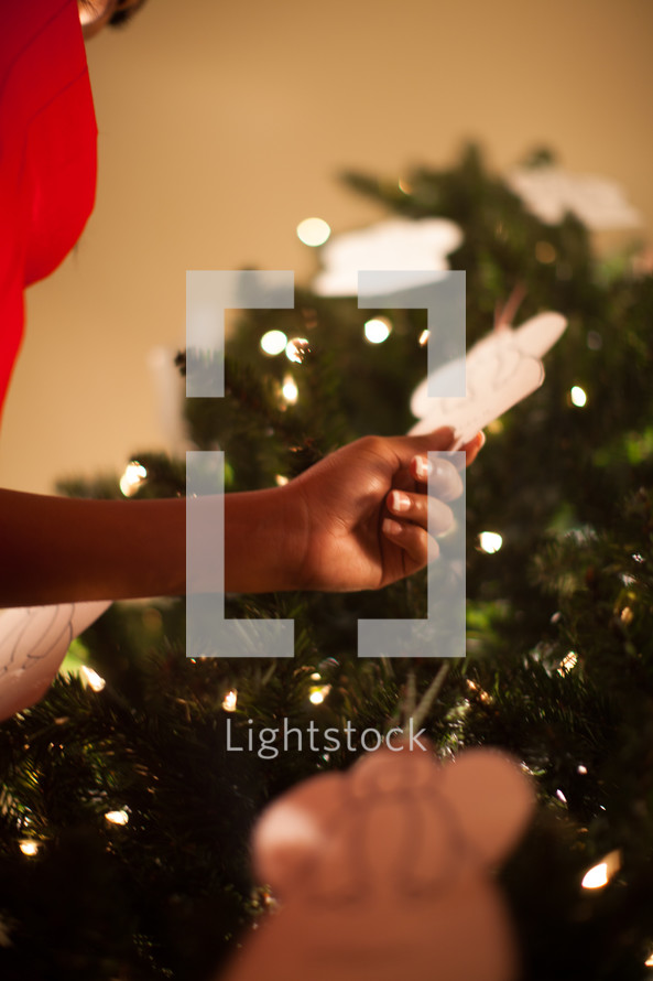A woman touching an angel ornament on a Christmas tree