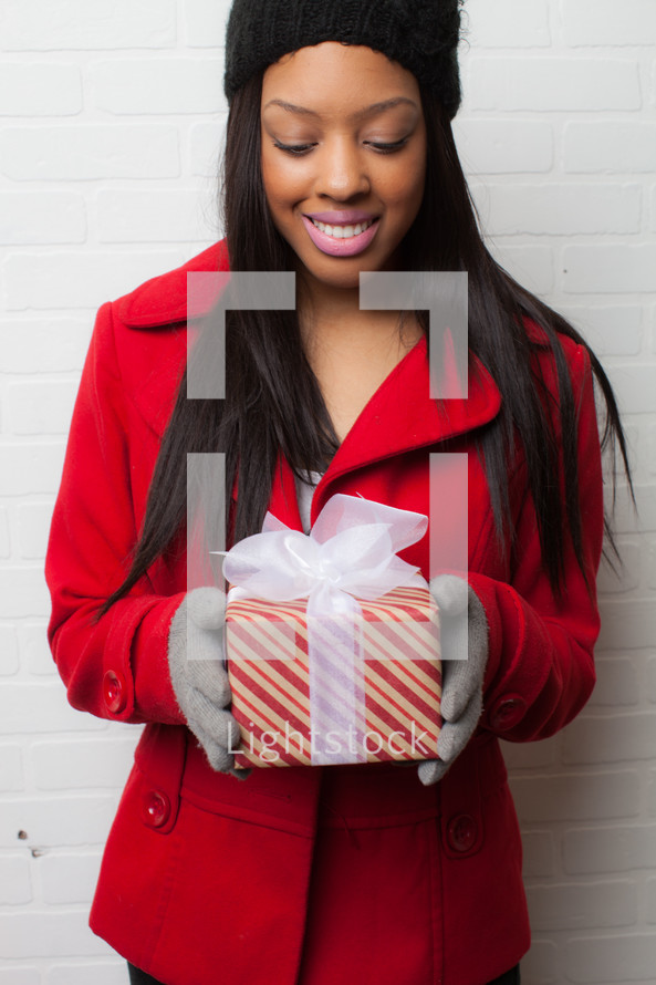 An African-American woman holding a wrapped Christmas gift 