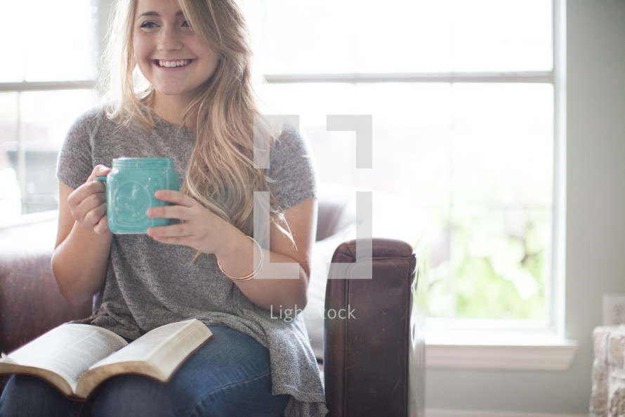 woman drinking coffee and reading a Bible on her lap 