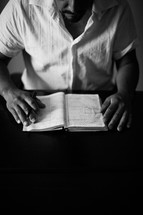 A man sitting at a table, studying a Bible.