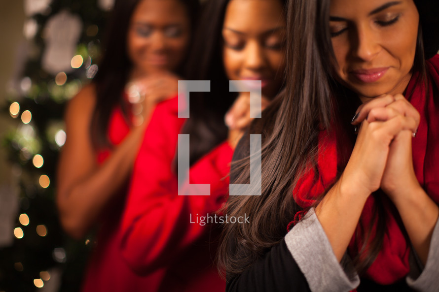 three African-American women in prayer at Christmas 