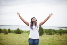 woman standing outdoors with hand raised to God 