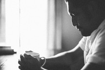 man in prayer holding a coffee mug