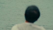 Asian man sitting looking towards the sea, rack focus shot
