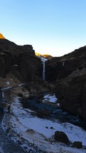 Waterfall At Distant Mountains In Winter Iceland