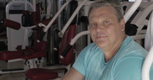Senior man with thumb up and smile between exercises in gym