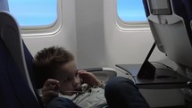 Child entertaining with mobile phone in the plane