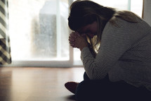 a pregnant woman sitting on the floor praying 