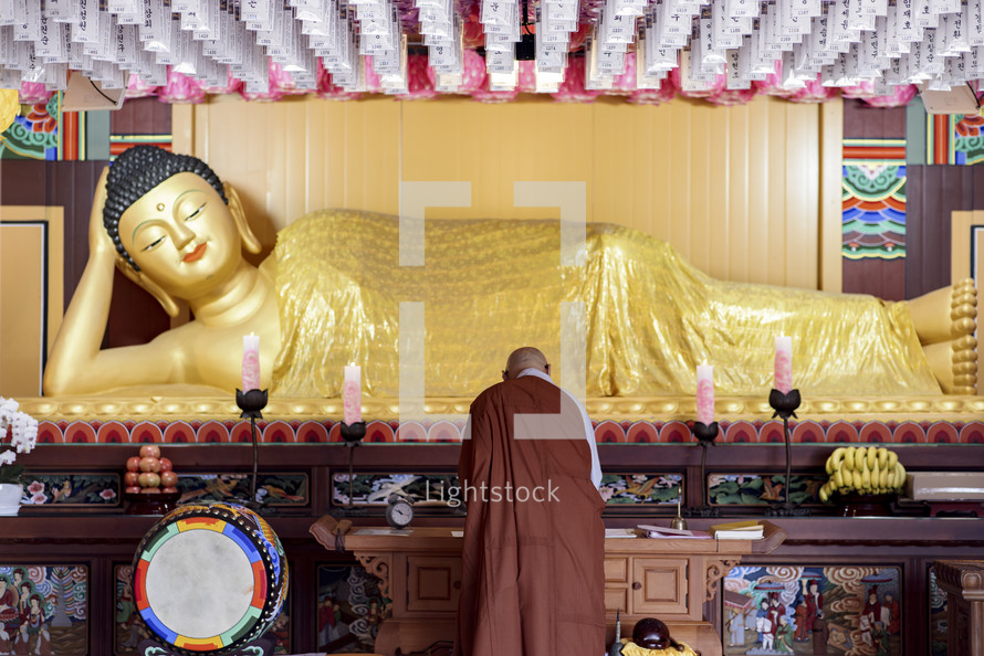 A Buddhist monk offering prayers to a lying Buddha