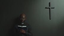 Black Priest Standing in Modern Church and Preaching with Bible