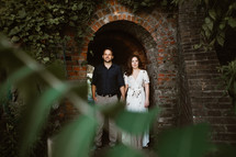 a couple standing under a brick arch 