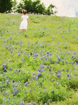 girl on a hillside covered with bluebonnet plants with an art effect