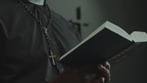 Black Priest Reading Bible and Leading Congregation in Prayer