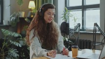 Pretty Female Blogger Making Audio Podcast or Live Streaming in Studio
