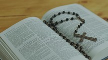 Opened Bible Book with Rosary Beads on Pages